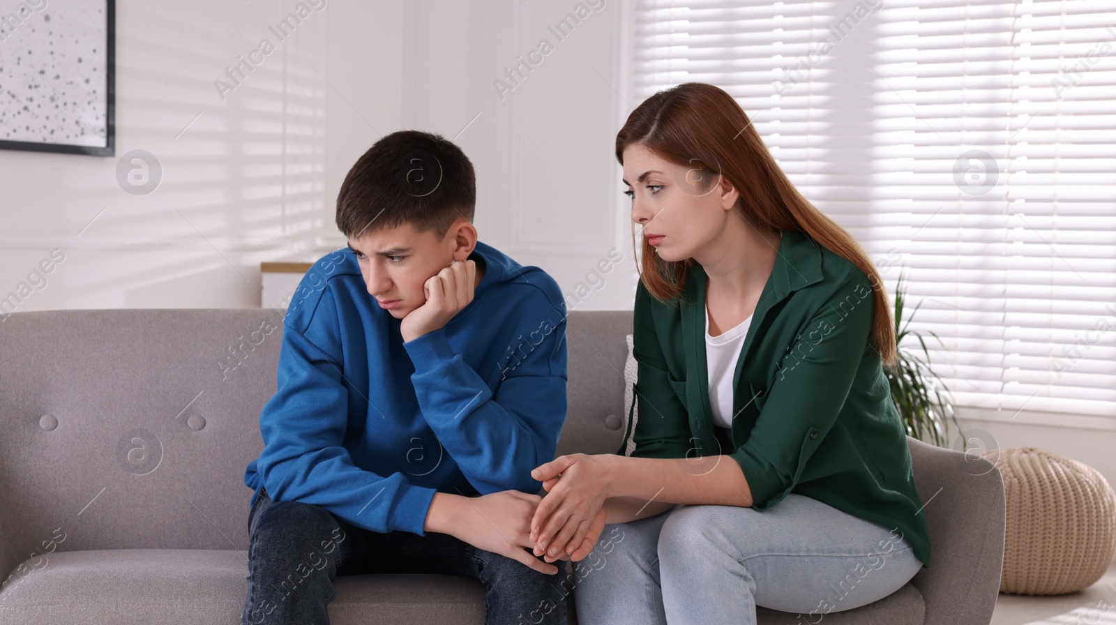 Photo of Mother consoling her depressed son at home. Teenager problems