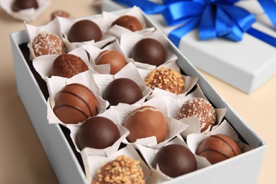 Photo of Box with delicious chocolate candies on beige background, closeup