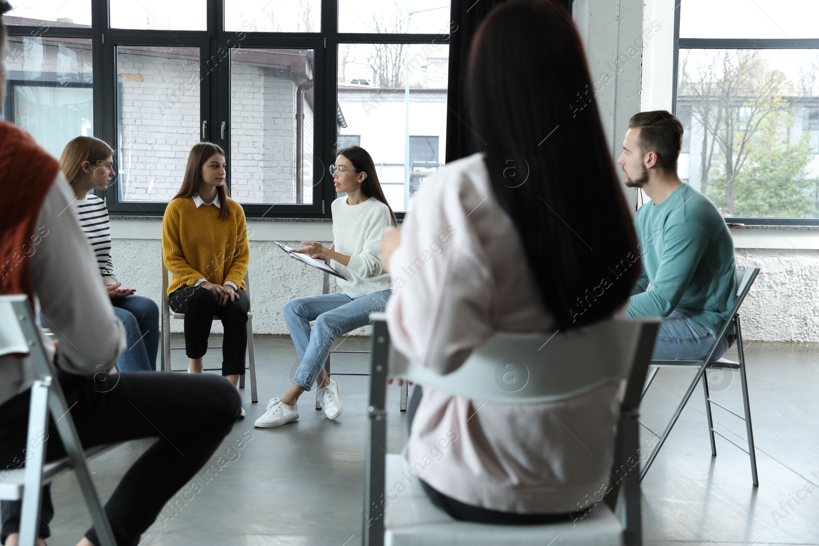 Photo of Psychotherapist working with patients in group therapy session indoors