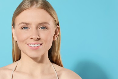 Beautiful young woman posing on light blue background, space for text
