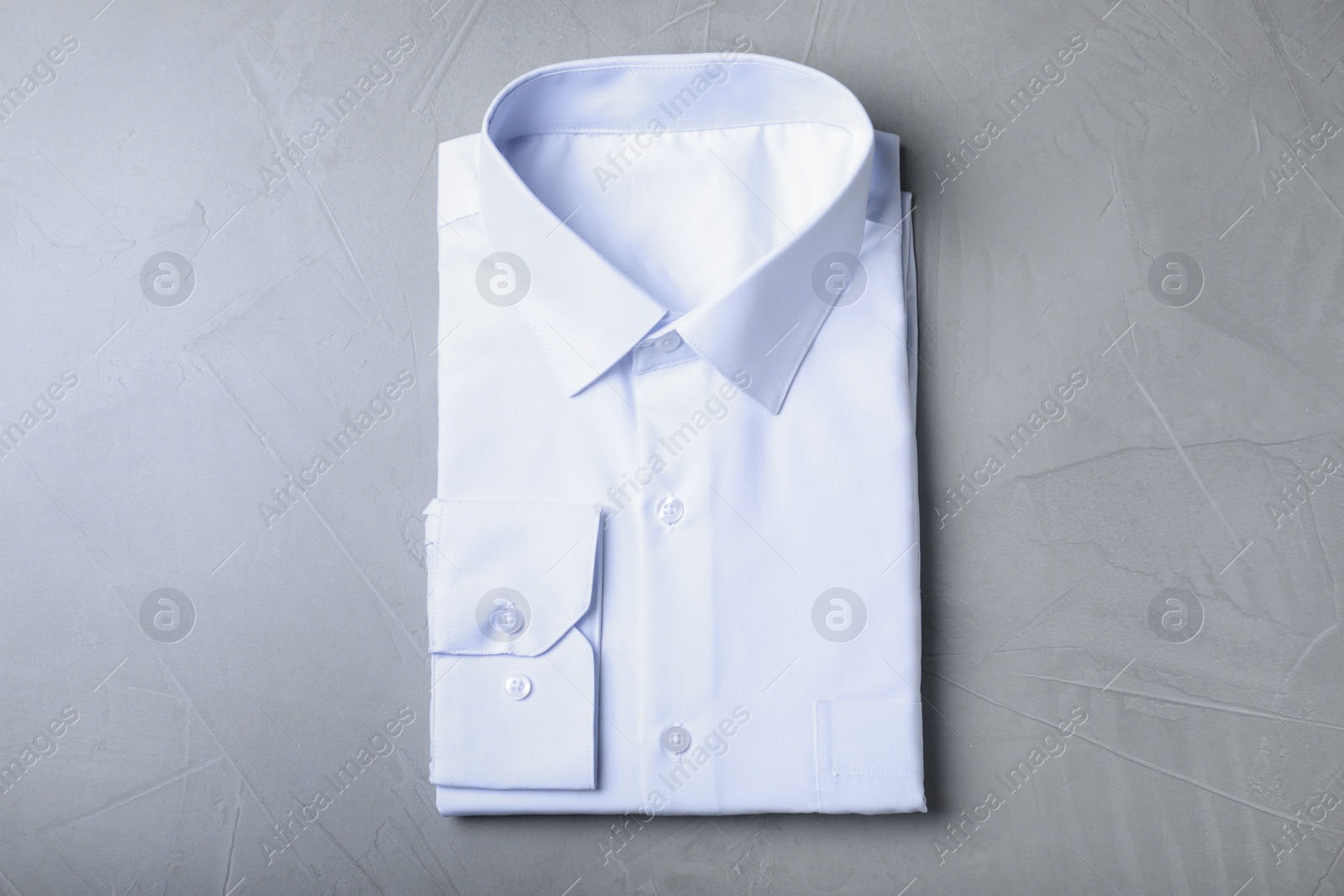 Photo of Stylish white shirt on grey background, top view. Dry-cleaning service