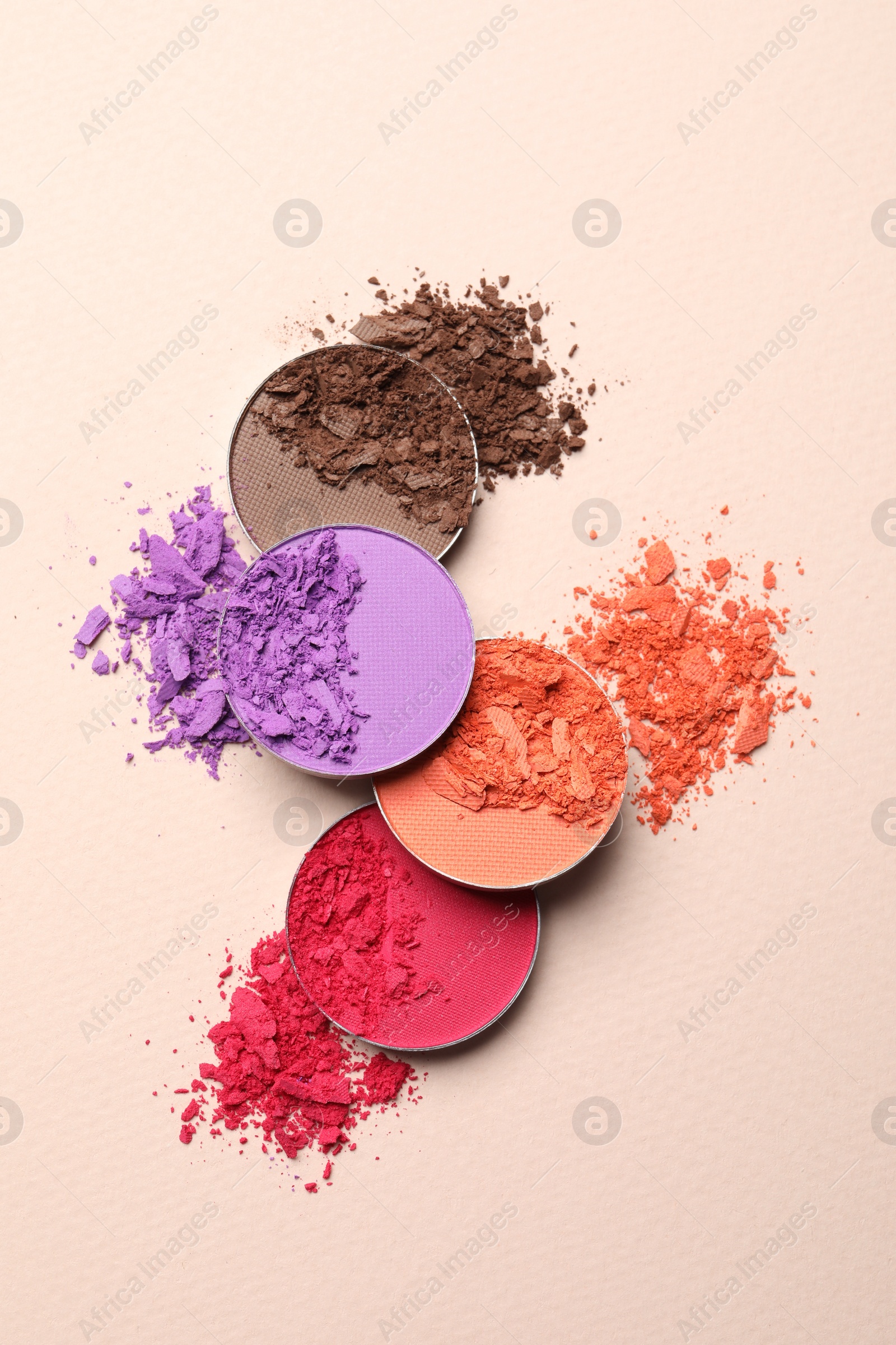 Photo of Different crushed eye shadows on beige background, flat lay