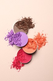 Photo of Different crushed eye shadows on beige background, flat lay