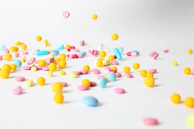 Different pills falling on table against white background