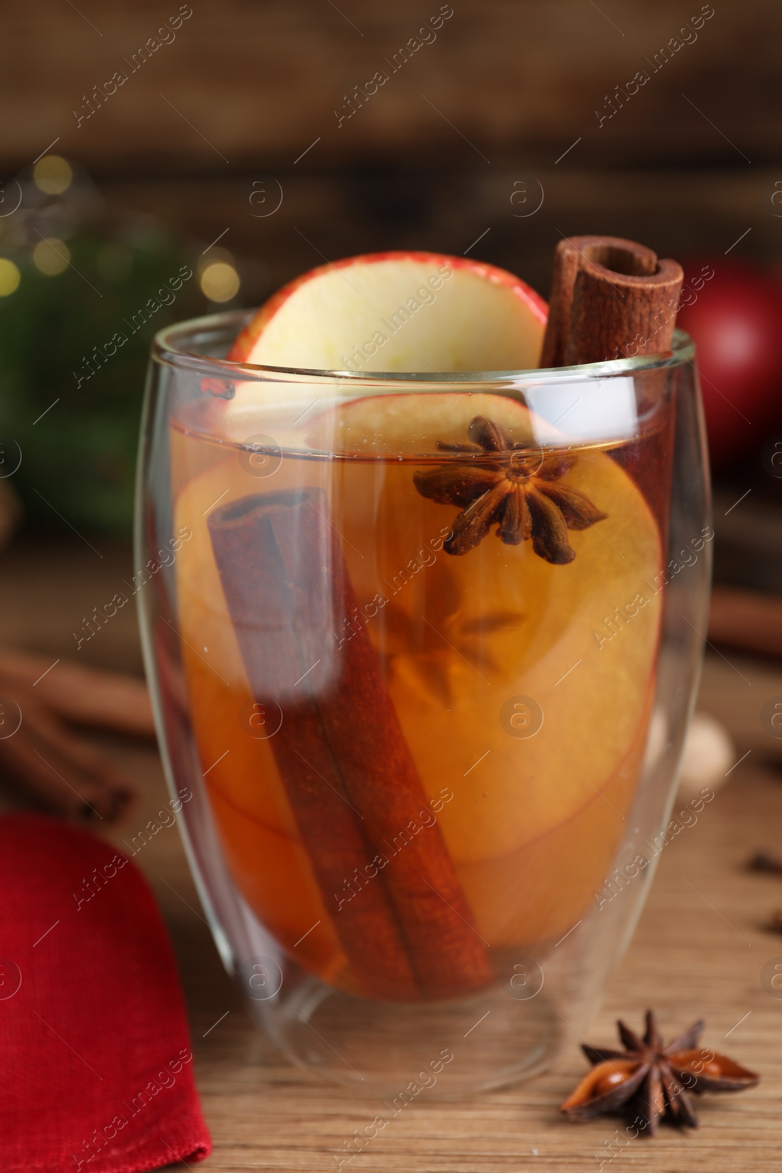 Photo of Hot mulled cider on wooden table, closeup