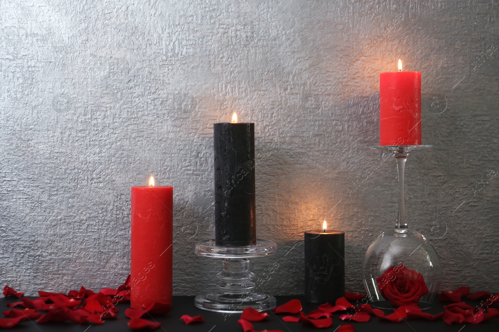 Photo of Candles with floral decor on table against color background