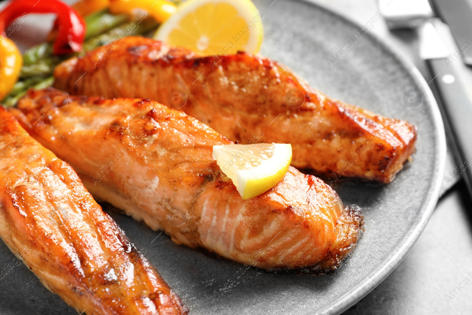 Photo of Tasty cooked salmon with lemon on plate, closeup