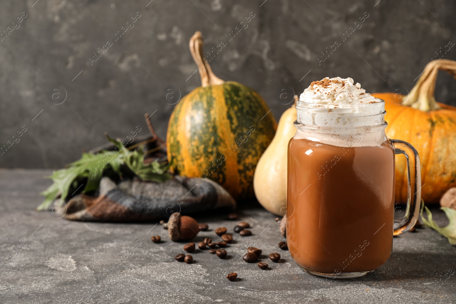 Photo of Mason jar with tasty pumpkin spice latte on grey table. Space for text