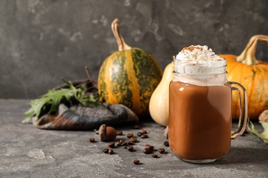 Mason jar with tasty pumpkin spice latte on grey table. Space for text