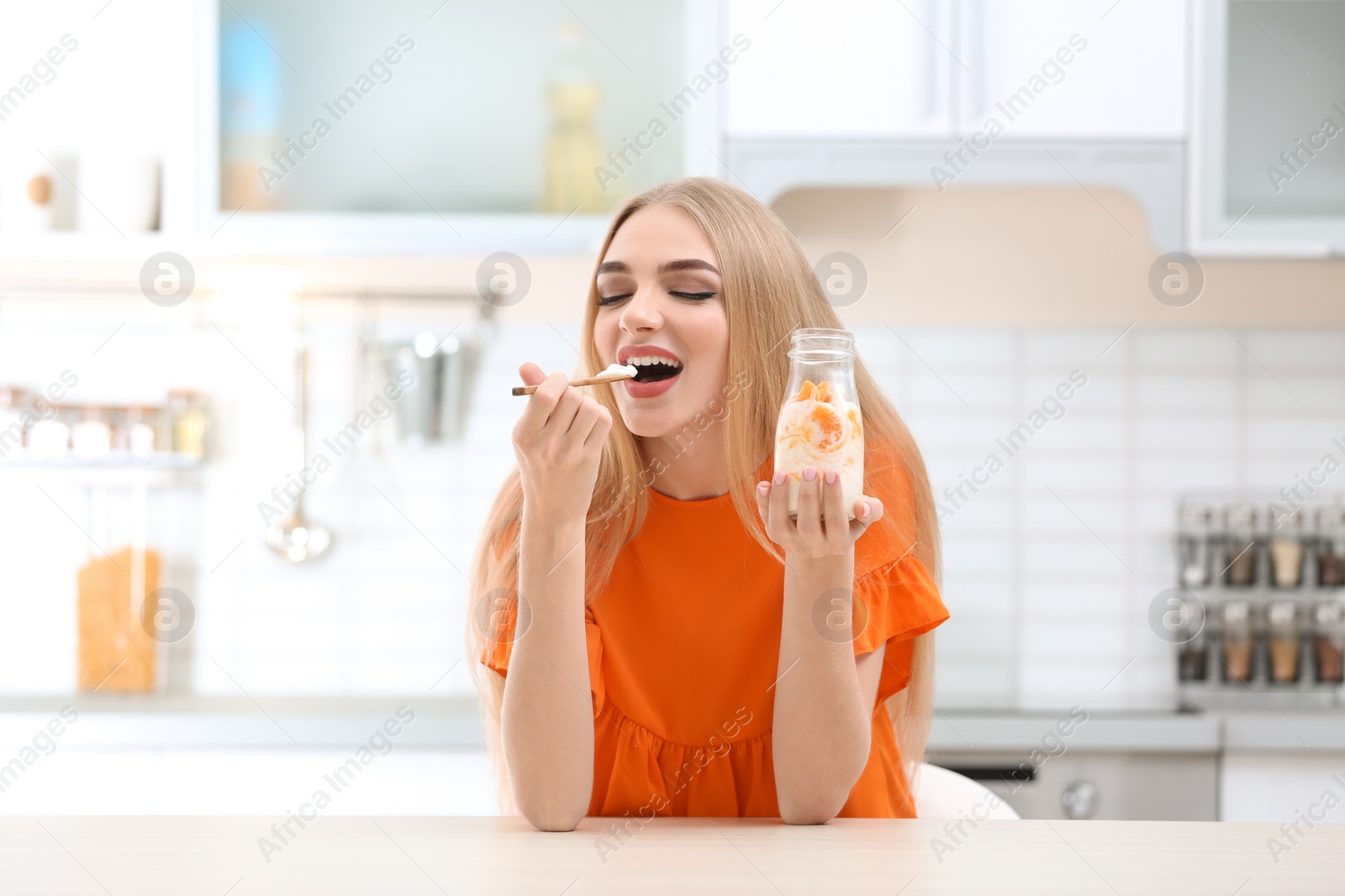 Photo of Young woman with yogurt in kitchen