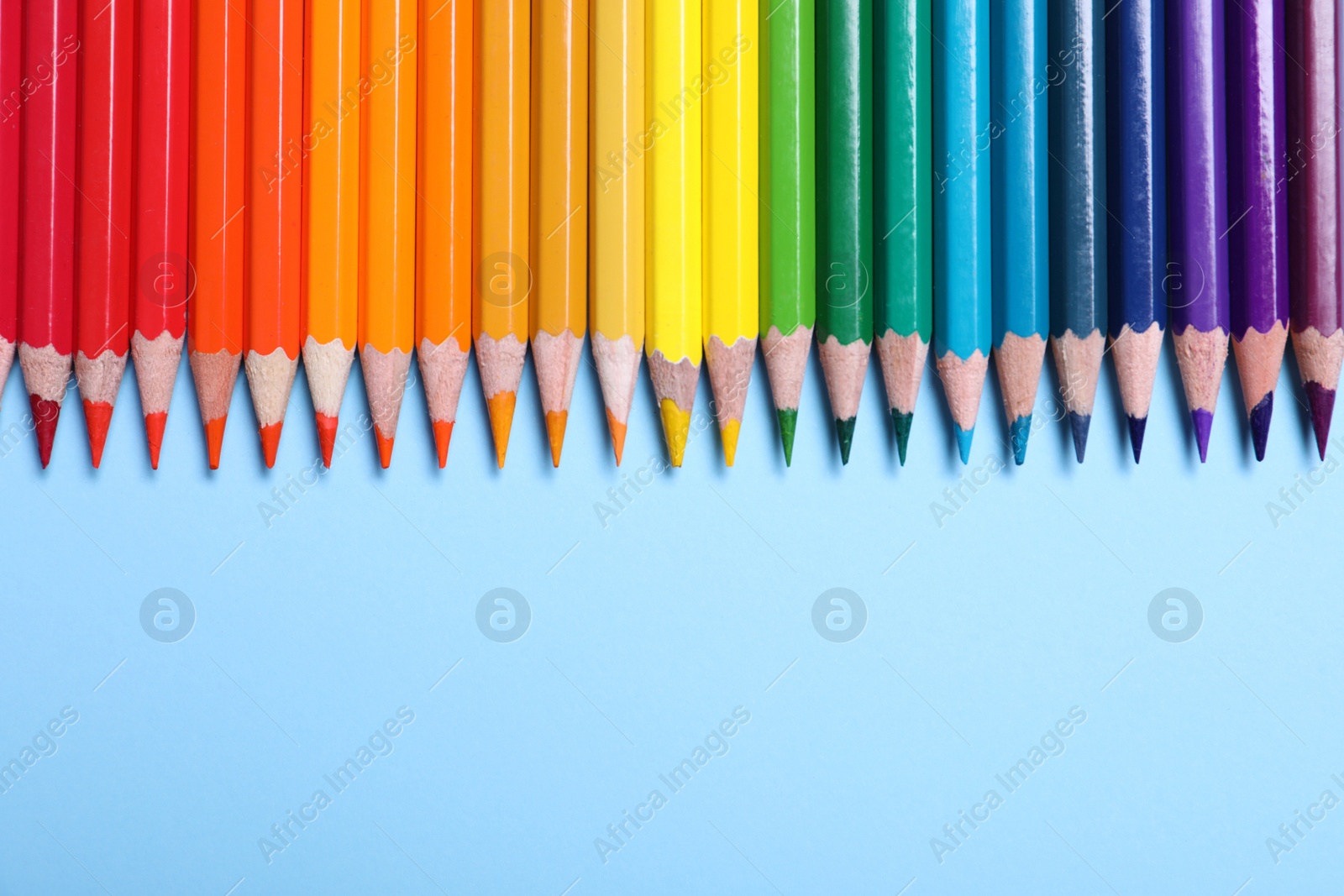 Photo of Colorful pencils on light blue background, flat lay. Space for text