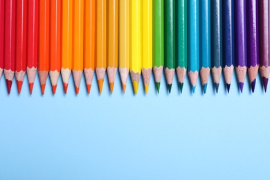 Photo of Colorful pencils on light blue background, flat lay. Space for text