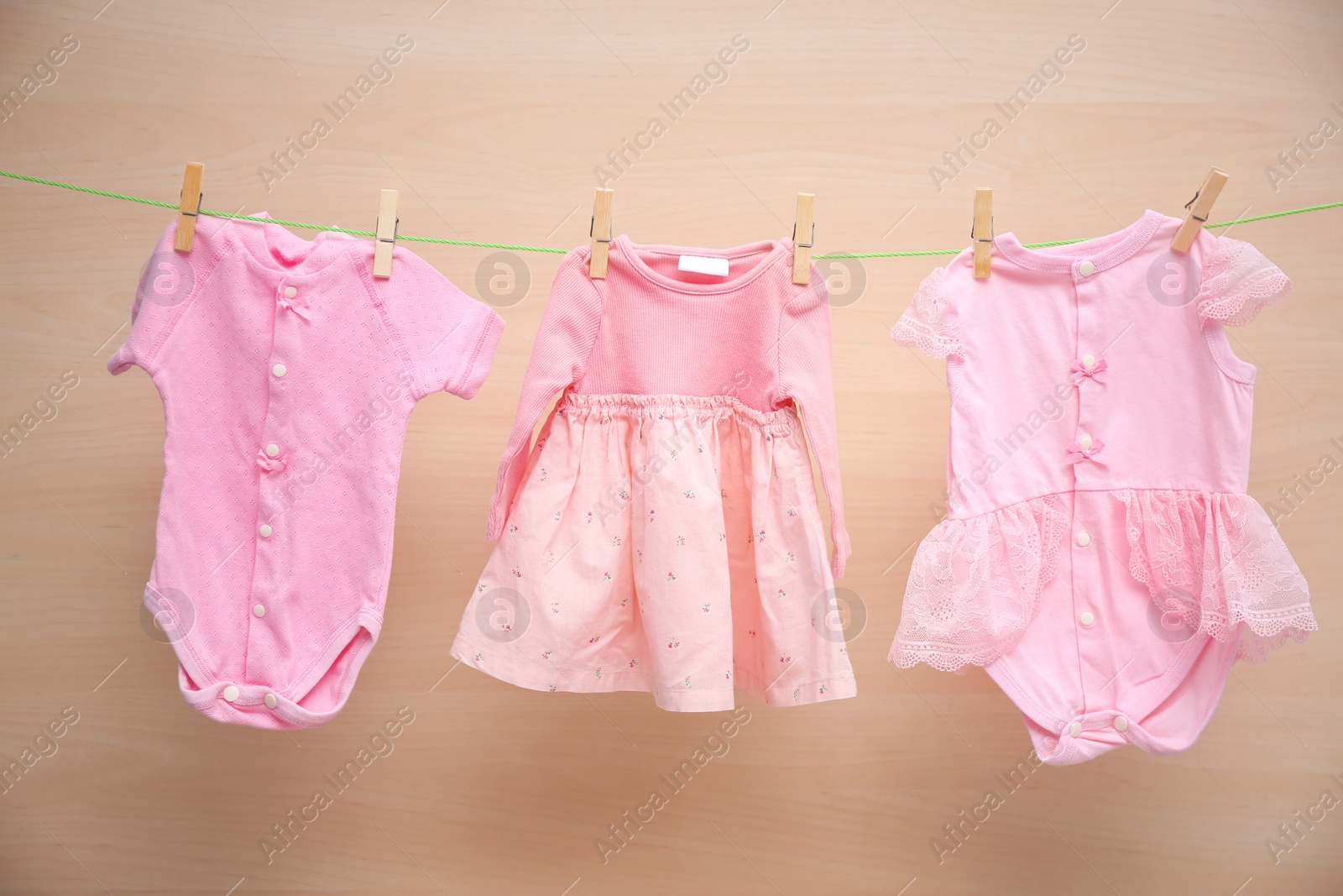 Photo of Baby clothes hanging on washing line against wooden background