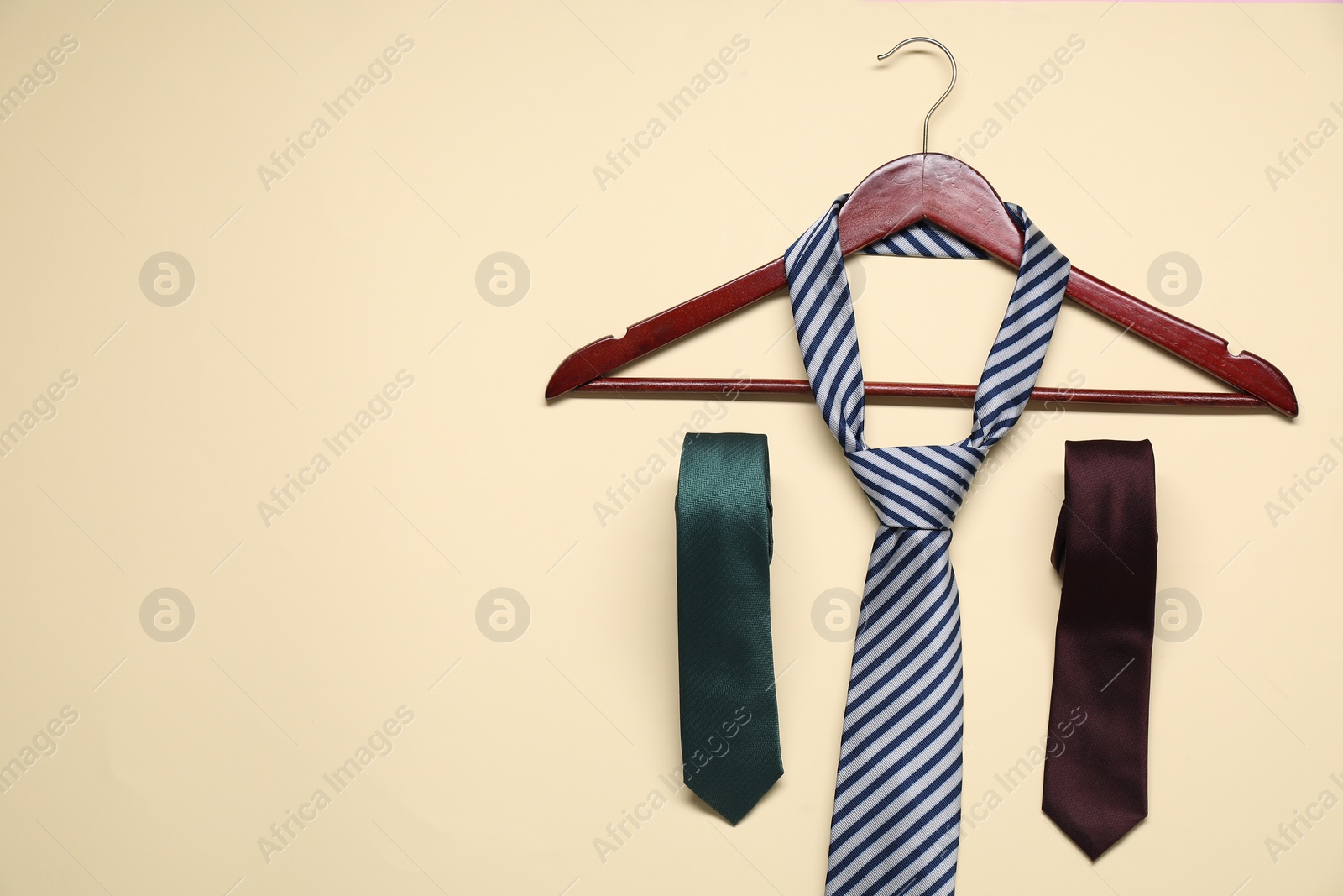 Photo of Hanger and neckties on beige background, flat lay. Space for text