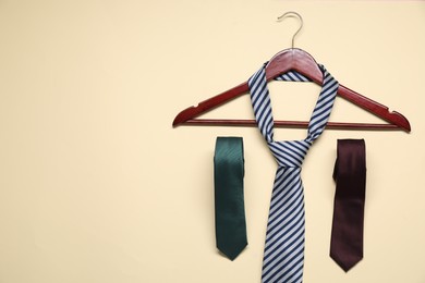 Photo of Hanger and neckties on beige background, flat lay. Space for text