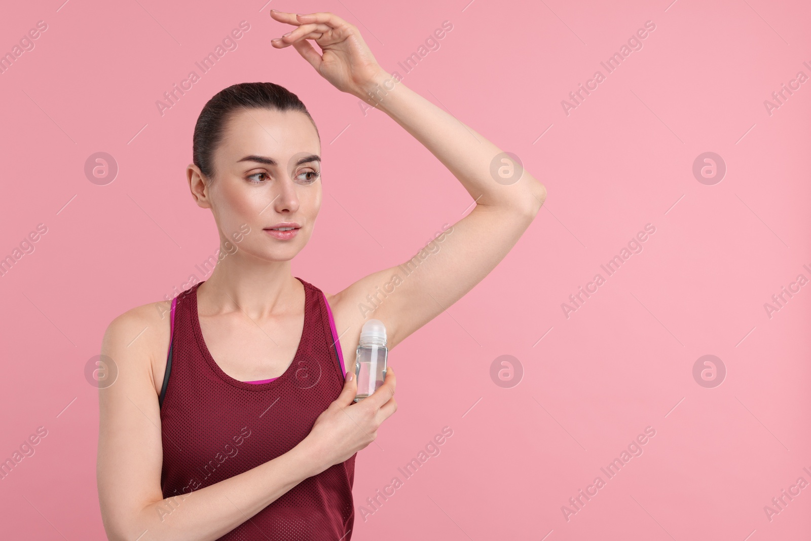 Photo of Beautiful woman applying deodorant on pink background, space for text