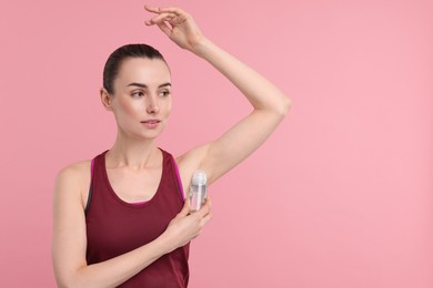 Photo of Beautiful woman applying deodorant on pink background, space for text