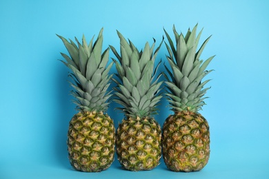 Photo of Ripe juicy pineapples on light blue background