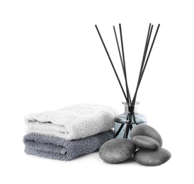 Photo of Spa stones, reed air freshener and towels on white background