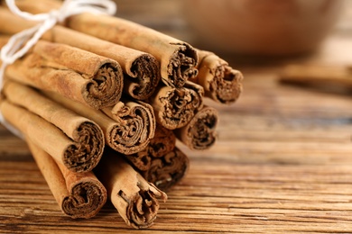 Aromatic cinnamon sticks on wooden table, closeup. Space for text