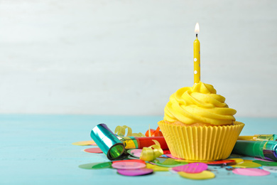 Photo of Delicious birthday cupcake with cream and burning candle on blue wooden background. Space for text