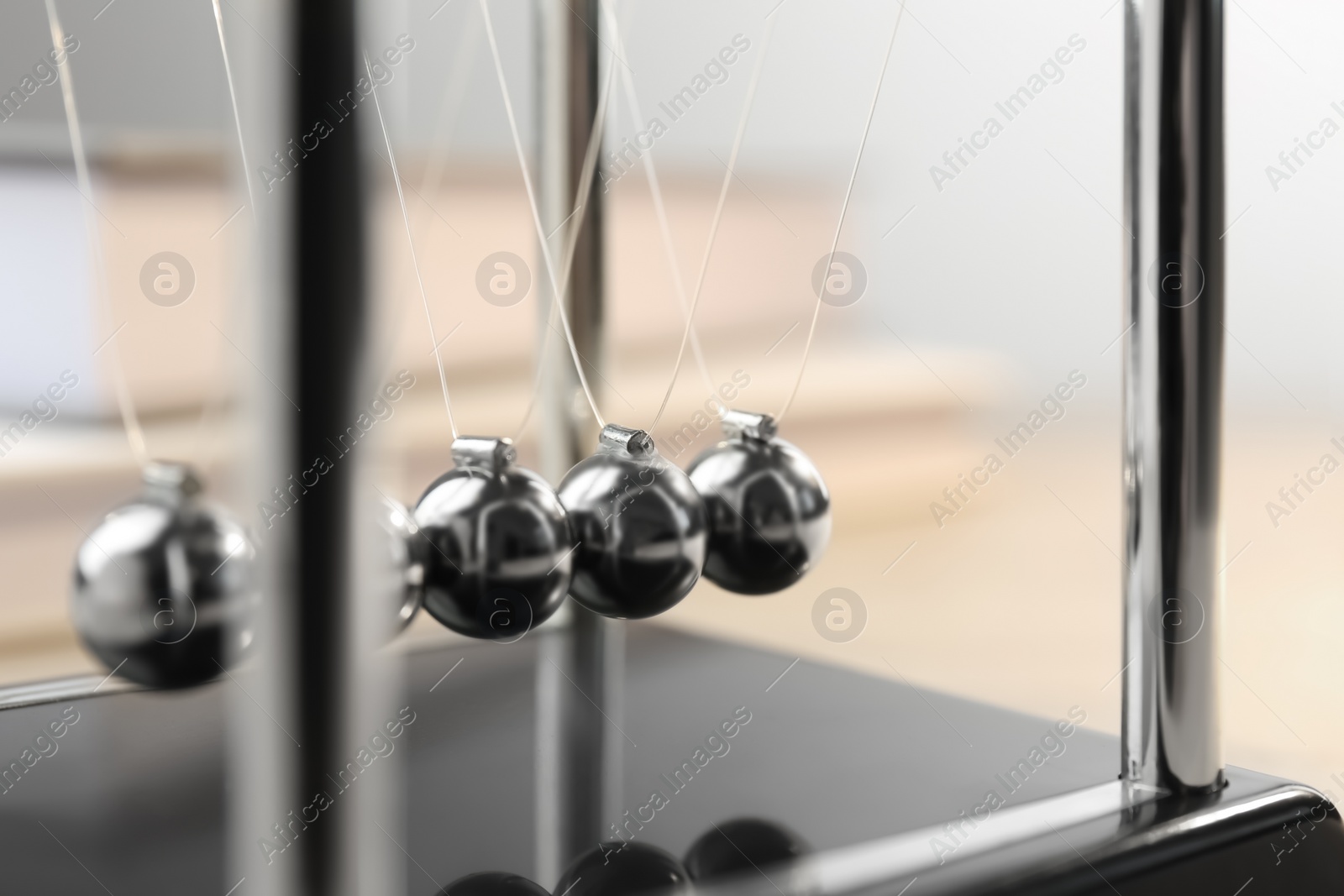 Photo of Newton's cradle on table, closeup. Physics law of energy conservation