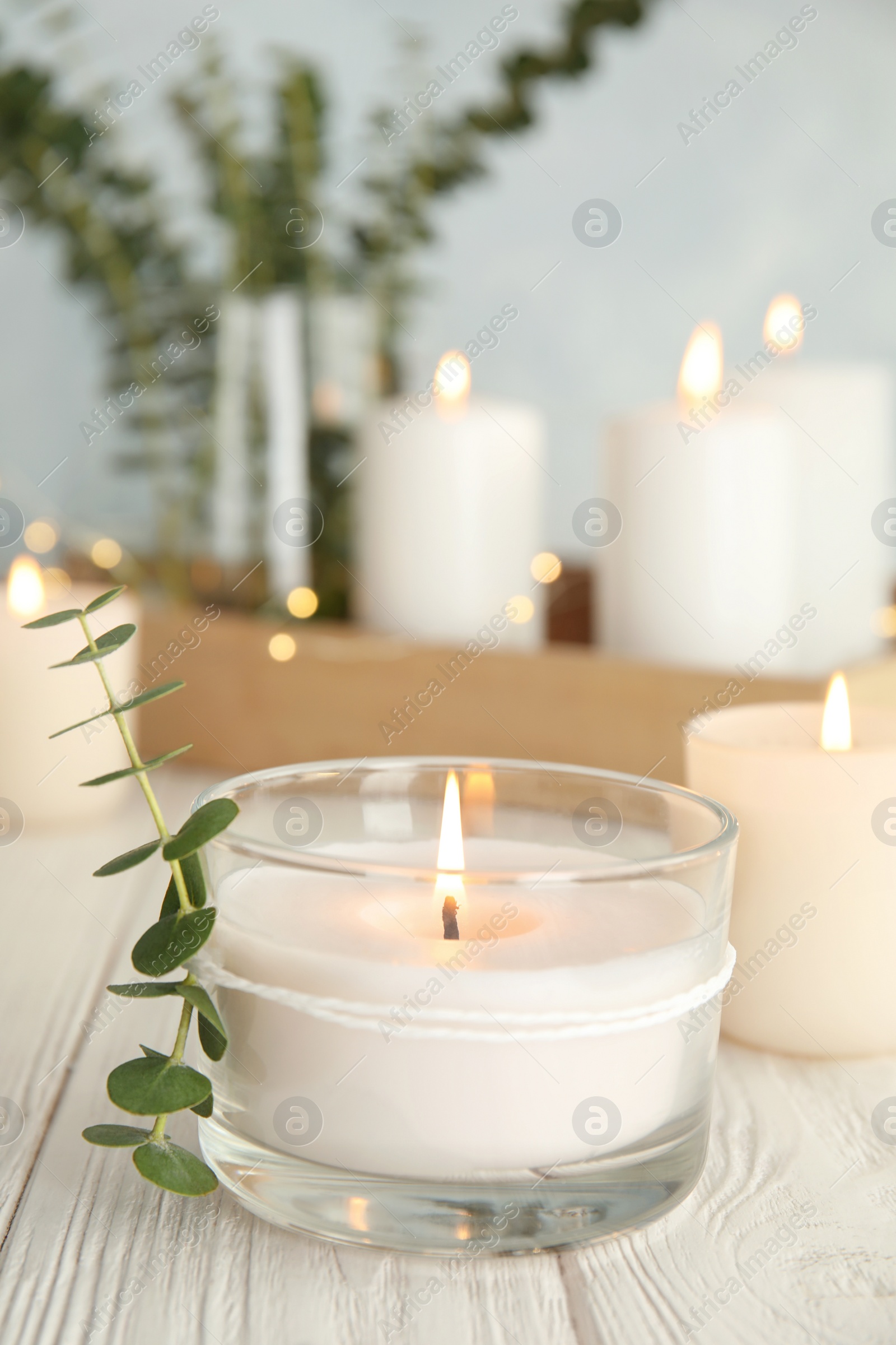 Photo of Burning aromatic candle and eucalyptus branch on table. Space for text