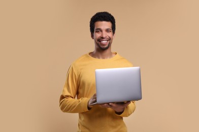 Photo of Happy man with laptop on beige background