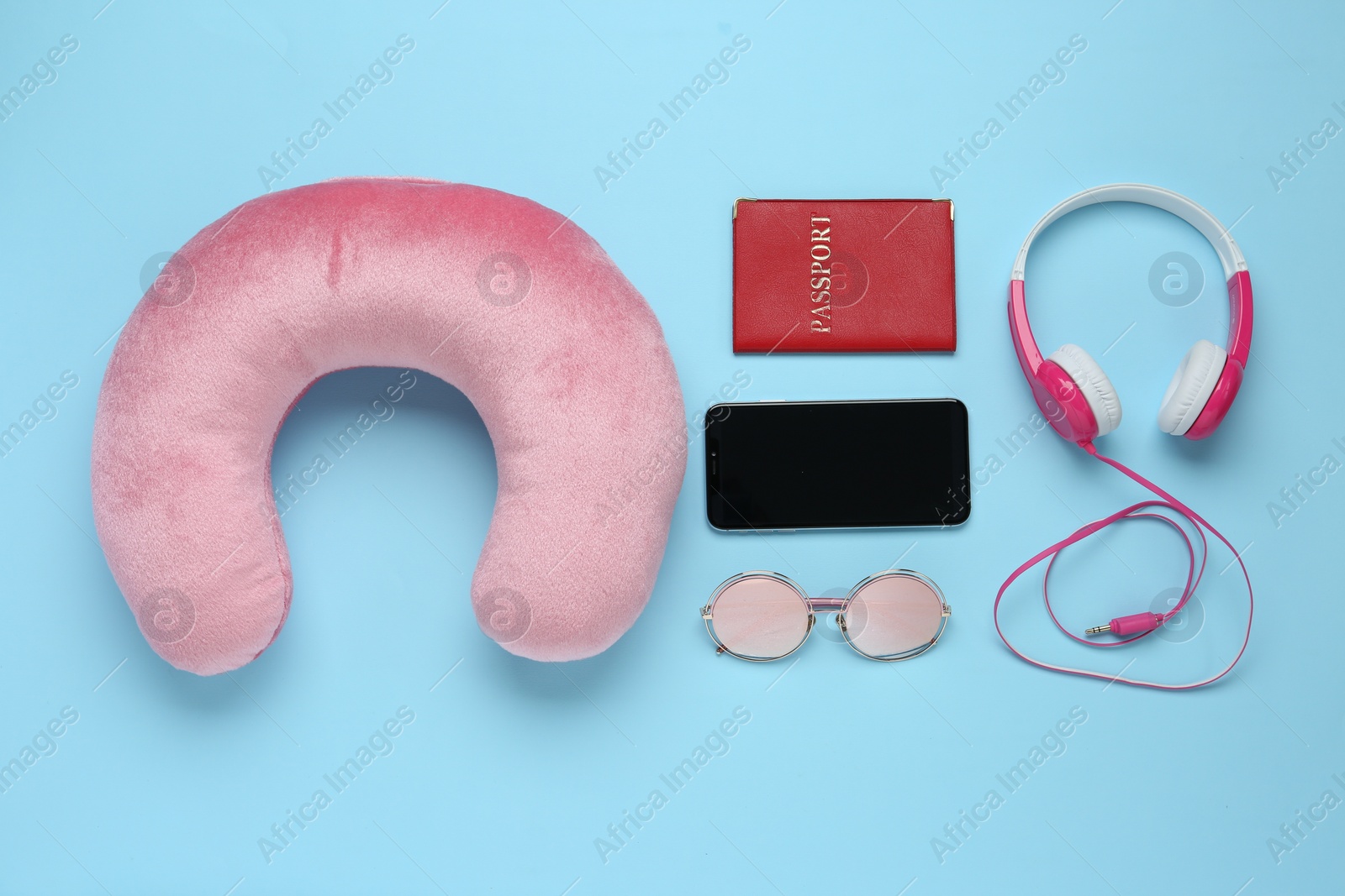 Photo of Flat lay composition with pink travel pillow and smartphone on light blue background