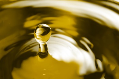 Image of Splash of golden oily liquid with drop as background, closeup. Space for text