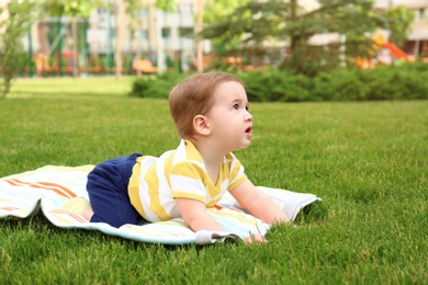 Photo of Adorable little baby crawling on blanket outdoors