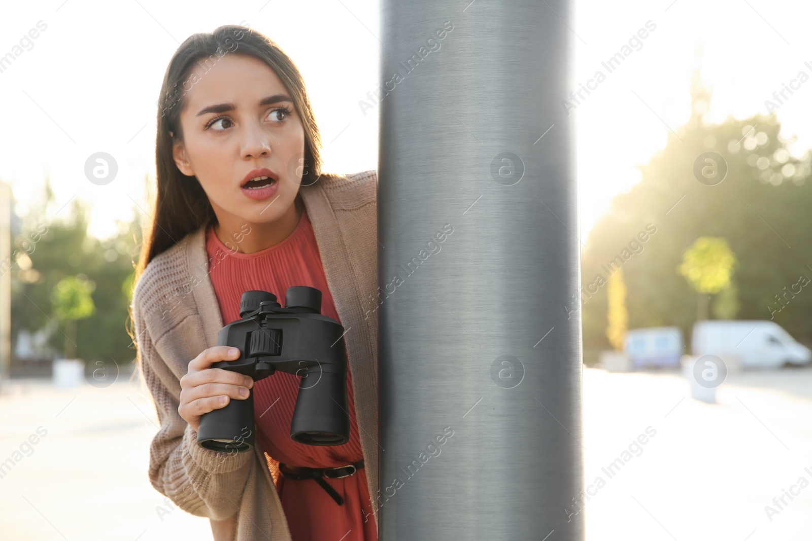 Photo of Jealous woman with binoculars spying on ex boyfriend outdoors