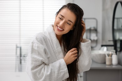 Photo of Smiling woman wearing bathrobe after shower in bathroom