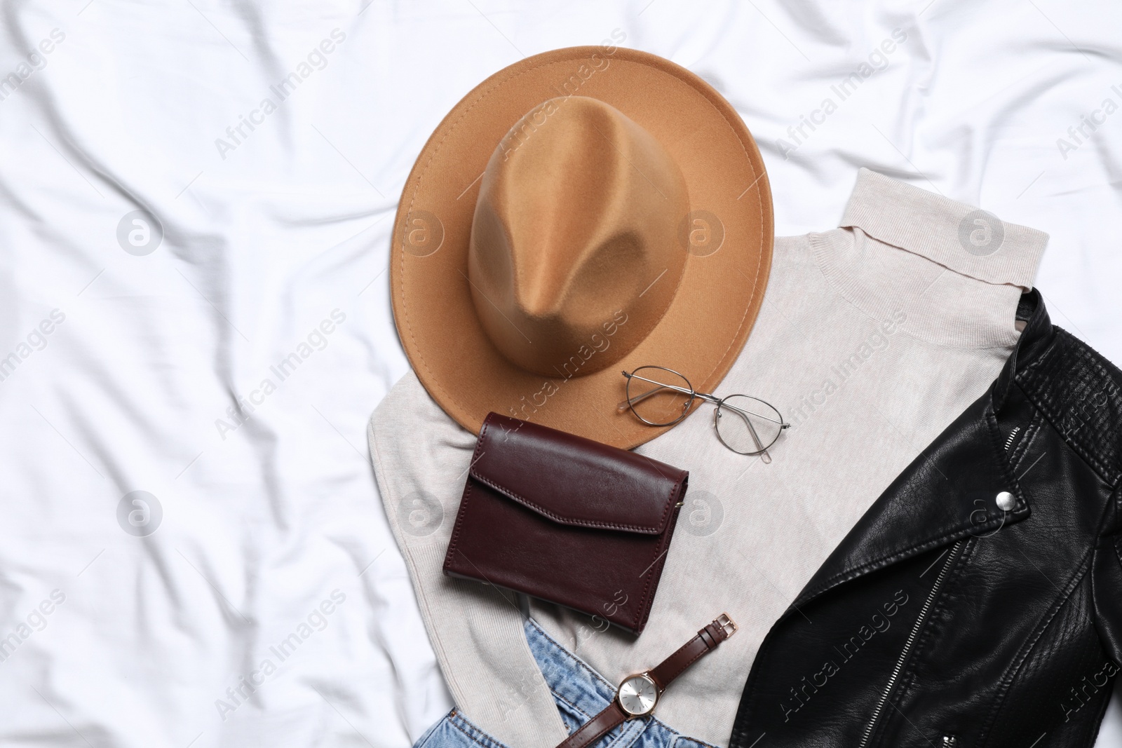 Photo of Flat lay composition with stylish hat and autumn clothes on white fabric, space for text
