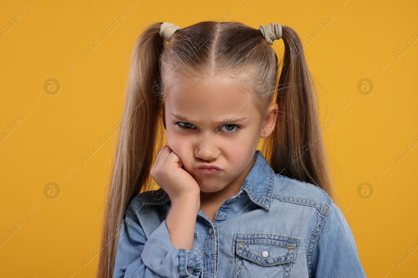 Photo of Portrait of resentful girl on orange background