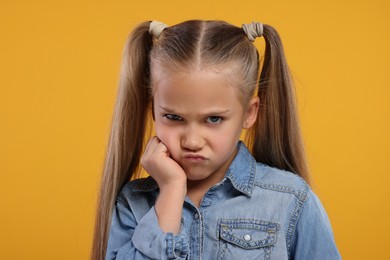 Portrait of resentful girl on orange background