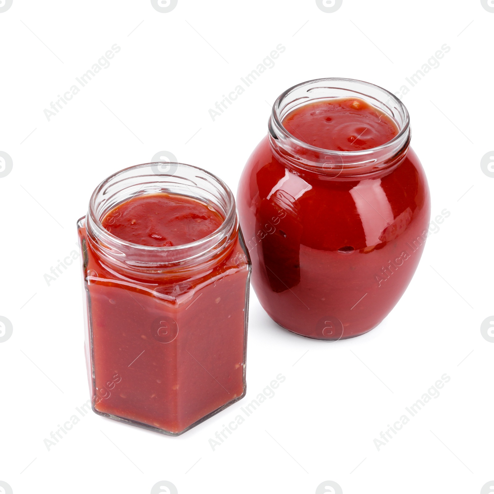 Photo of Organic ketchup in glass jars isolated on white. Tomato sauce