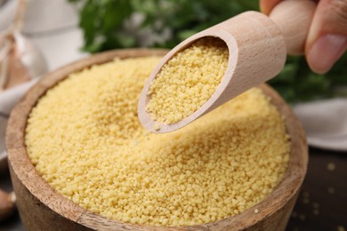 Photo of Taking raw couscous with scoop from bowl, closeup