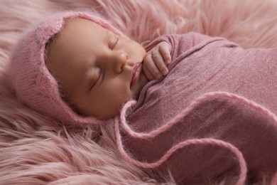 Photo of Adorable newborn baby lying on faux fur, closeup
