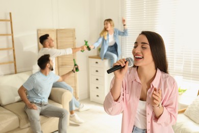 Photo of Young woman singing karaoke with friends at home