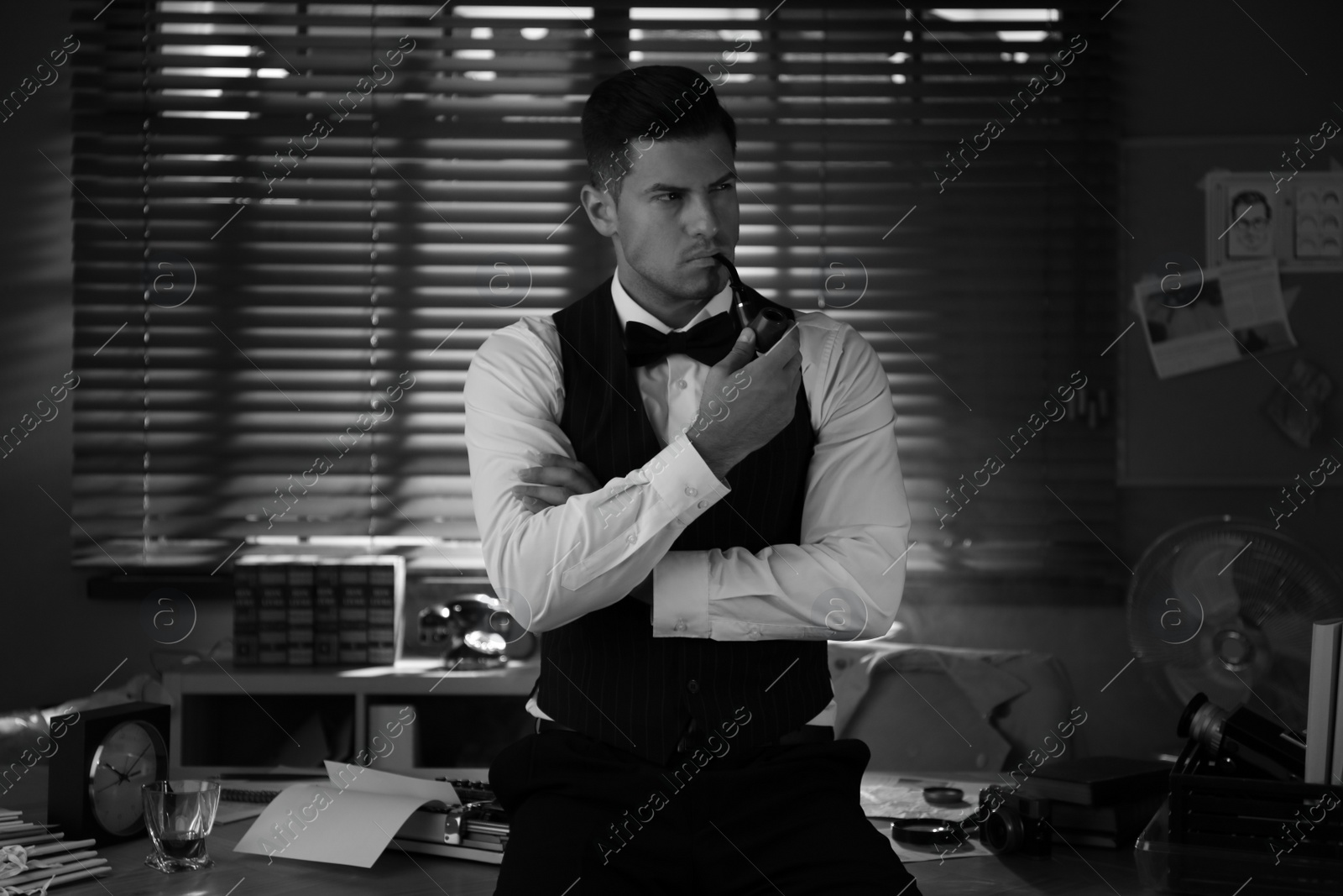 Photo of Old fashioned detective with smoking pipe in office. Black and white effect