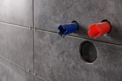 Wall with grey modern tiles and holes for sink