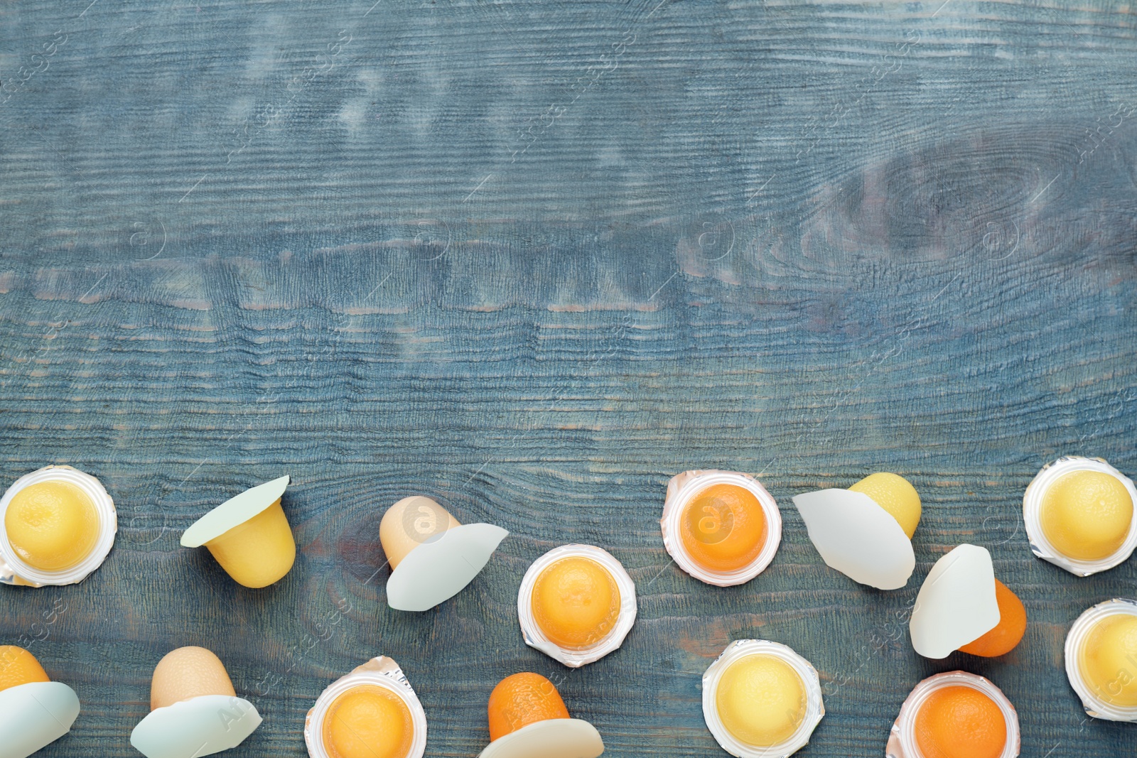 Photo of Tasty bright jelly cups on blue wooden table, flat lay. Space for text