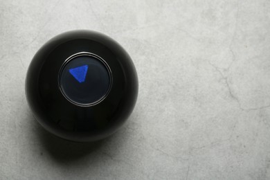 Magic eight ball on grey table, above view. Space for text