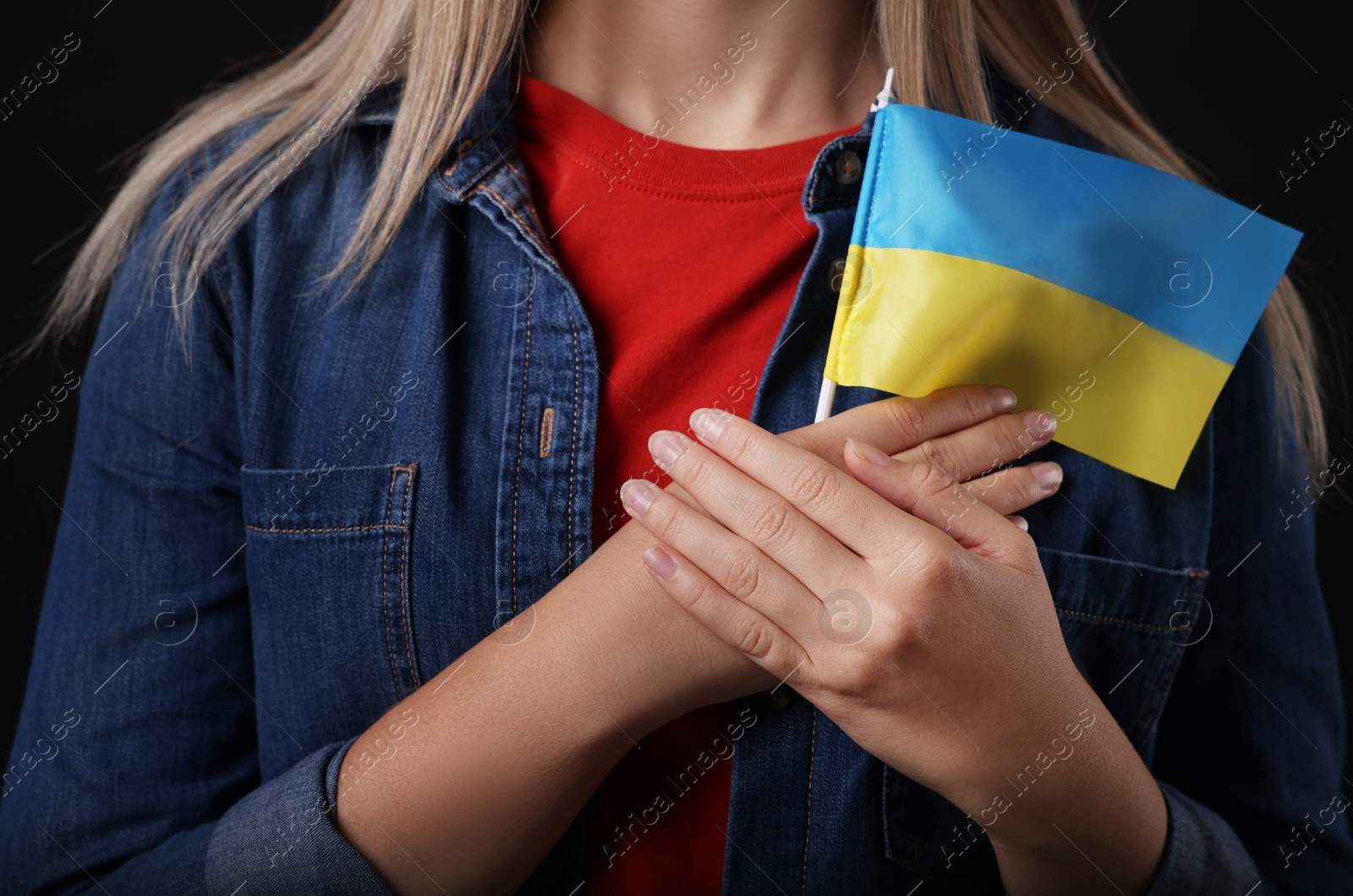 Photo of Woman holding Ukrainian flag on black background, closeup