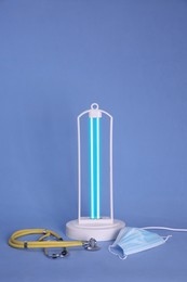 Photo of Ultraviolet lamp, medical mask and stethoscope on background