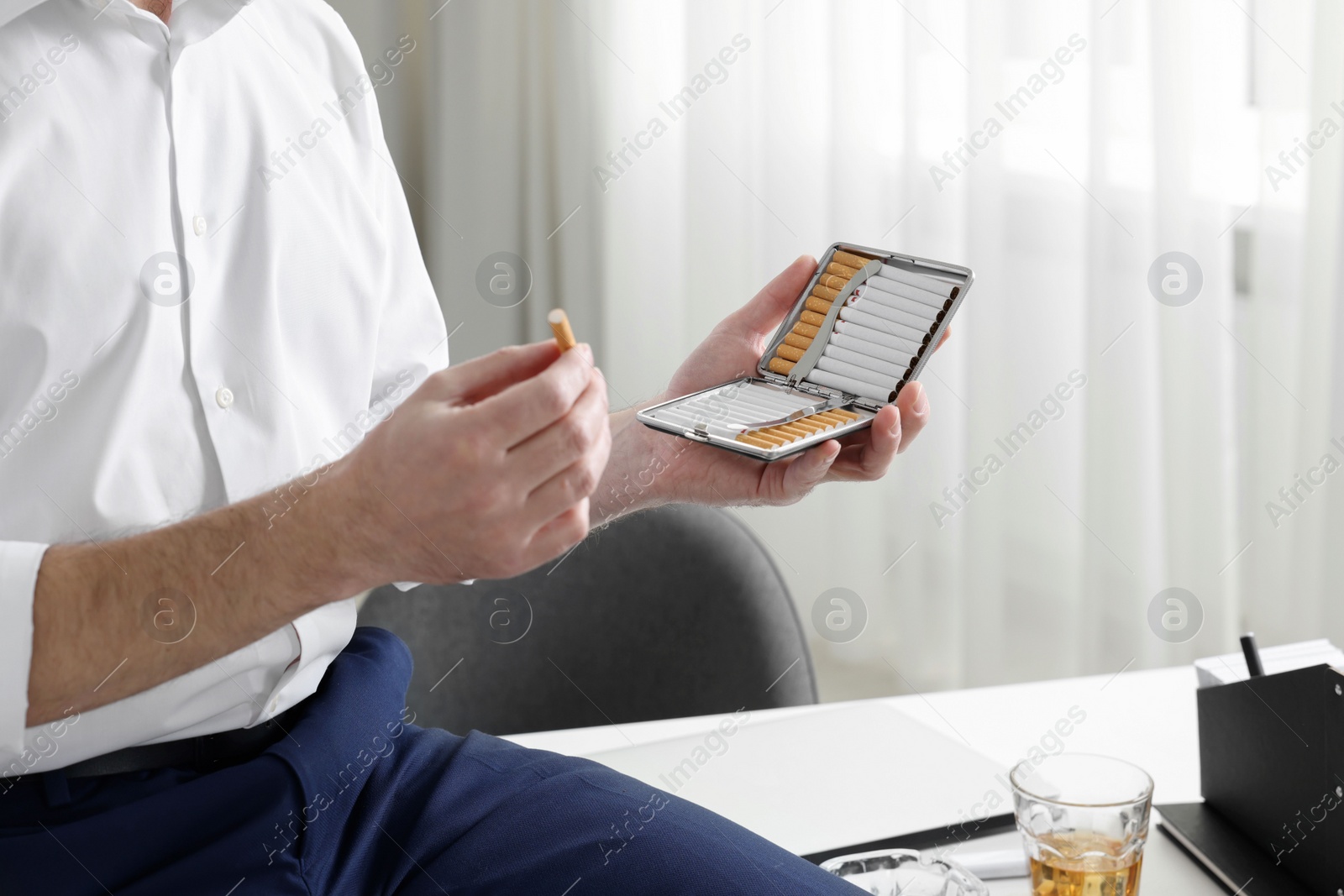 Photo of Man with cigarette and case in office, closeup. Space for text