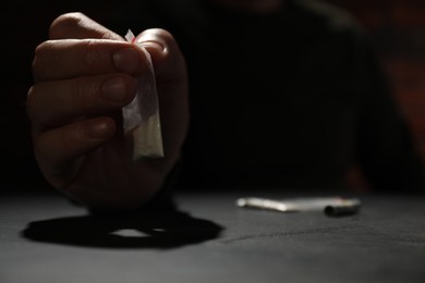 Drug addiction. Man with plastic bag of cocaine at grey table, selective focus