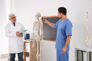 Photo of Medical student and professor studying human skeleton anatomy in classroom