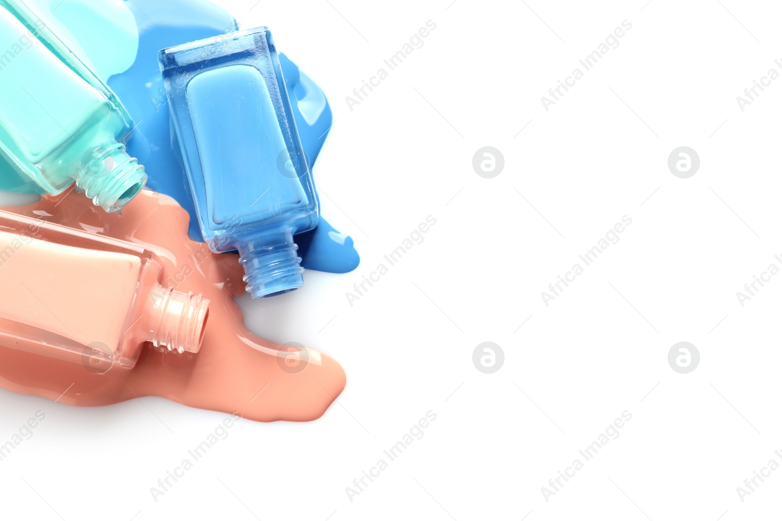 Photo of Spilled different nail polishes with bottles on white background, top view